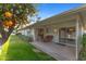 Covered patio with seating area, overlooking lush green lawn and mature orange tree at 12814 W Shadow Hills Dr, Sun City West, AZ 85375