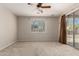 A simple bedroom features carpet, a ceiling fan, and a sliding glass door to the backyard at 27250 N 86Th Ave, Peoria, AZ 85383