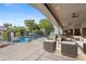 A covered patio offers a seating area overlooking the pool with mature landscaping for ideal outdoor living at 4914 N Valley Gln, Litchfield Park, AZ 85340