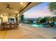 A covered patio features a dining table and seating area that overlooks the pool and lush landscaping at 4914 N Valley Gln, Litchfield Park, AZ 85340