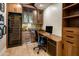 This home office features built in cabinets, desk, a wine cooler, and hardwood floors at 6166 N Scottsdale Rd # A3001, Paradise Valley, AZ 85253