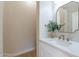 Elegant powder room with a white vanity, a modern mirror, and a vase with greenery at 3063 E Warbler Rd, Gilbert, AZ 85297