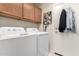 Bright laundry area features a washer, dryer, and upper cabinets for organized storage solutions at 3403 E Kristal Way, Phoenix, AZ 85050