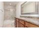 Bathroom featuring a tiled shower, granite countertops, a decorative mirror, and neutral color palette at 36923 N 31St Ave, Phoenix, AZ 85086