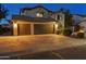 Lovely two-story home featuring a three-car garage and well manicured front yard at twilight at 586 E Stirrup Ln, San Tan Valley, AZ 85143