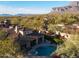 High angle view of a luxury house featuring a backyard pool, spa, covered outdoor kitchen, and lush landscaping at 8057 E Greythorn Dr, Gold Canyon, AZ 85118