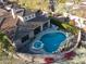 Aerial view of a luxurious backyard featuring a sparkling pool, spa, covered outdoor kitchen, and lush landscaping at 8057 E Greythorn Dr, Gold Canyon, AZ 85118