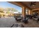 Relaxing covered patio with stylish seating, fan, and a view of the beautifully landscaped backyard and pool at 8057 E Greythorn Dr, Gold Canyon, AZ 85118