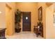 Inviting home foyer featuring a charming wooden bench, lush plant and elegant travertine flooring at 8057 E Greythorn Dr, Gold Canyon, AZ 85118