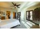This bedroom features a ceiling fan, a king bed, plantation shutters, bedside tables with lamps, and french doors at 8057 E Greythorn Dr, Gold Canyon, AZ 85118