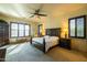 This main bedroom features a ceiling fan, a king bed, bedside tables, and plantation shutters at 8057 E Greythorn Dr, Gold Canyon, AZ 85118