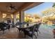 Inviting outdoor patio featuring a dining table with seating, fireplace, and a view of the pool and desert landscaping at 8057 E Greythorn Dr, Gold Canyon, AZ 85118