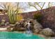 View of the pool featuring a rock waterfall with desert plants behind it at 8057 E Greythorn Dr, Gold Canyon, AZ 85118