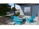 Relaxing backyard with bright blue Adirondack chairs around a fire pit, and a glimpse of the refreshing pool and landscaping at 10309 E Supernova Dr, Mesa, AZ 85212