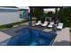 A modern pool with a pergola-covered lounge area featuring stone pillars and comfortable lounge chairs for relaxing poolside at 10309 E Supernova Dr, Mesa, AZ 85212