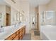 Bright bathroom with double sinks, wood cabinetry, a soaking tub, and a separate glass-enclosed shower at 1619 E Beretta Pl, Chandler, AZ 85286