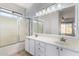 Bathroom with double sinks, large mirror, tub/shower combo with sliding doors and a window at 16848 W Bradford Way, Surprise, AZ 85374