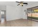 Open living room area with neutral tile flooring, a ceiling fan and sliding glass doors to the backyard at 16848 W Bradford Way, Surprise, AZ 85374