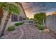 Backyard with stone path leading to an outdoor dining area with lush landscaping under a vibrant sky at 17675 N Coconino Dr, Surprise, AZ 85374
