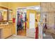 Bright bathroom featuring double sinks, granite countertop, mirrors, and walk-in closet with sliding doors at 17675 N Coconino Dr, Surprise, AZ 85374