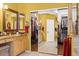 Bright bathroom featuring double sinks, granite countertop, mirrors, and walk-in closet with sliding doors at 17675 N Coconino Dr, Surprise, AZ 85374
