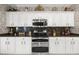 Traditional kitchen featuring white cabinets, stainless appliances, and decorative backsplash at 17675 N Coconino Dr, Surprise, AZ 85374
