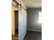 Stylish barn door and modern flooring enhances this bedroom with natural light and closet access at 3728 E Grove Ave, Mesa, AZ 85206