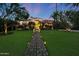 Stately home with lush lawn and illuminated stone pathway leading to the front entrance at 5710 E Camelback Rd, Phoenix, AZ 85018