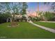 Spacious front yard with lush green lawn and mature trees surrounding the property at 5710 E Camelback Rd, Phoenix, AZ 85018
