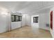 Open living area with tiled floor, exposed ceiling beams, bright natural light, and red door at 5710 E Camelback Rd, Phoenix, AZ 85018