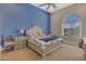 Comfortable bedroom showcasing a large bed, a striking blue accent wall, and a sunny arched window at 6938 E Lomas Verdes Dr, Scottsdale, AZ 85266