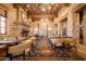 Elegant dining area with stone walls, exposed wood beams, a fireplace, and decorative chandeliers at 9161 E Superstition Mountain Dr, Gold Canyon, AZ 85118