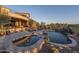 A luxurious pool with spa, waterfall feature, stone accents, and patio furniture overlooks the Arizona landscape at 9161 E Superstition Mountain Dr, Gold Canyon, AZ 85118