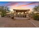 Stone pergola with shaded seating area offers a relaxing retreat amidst the desert landscape at 10718 E Fenimore Rd, Mesa, AZ 85207