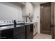 Functional laundry room with modern black appliances and white cabinetry at 11199 E Prospect Point Dr, Scottsdale, AZ 85262