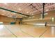 Community gymnasium featuring basketball hoops, bleacher seating, light wood flooring, and windows at 12343 W Essig Way, Peoria, AZ 85383