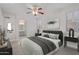 A staged primary bedroom with a ceiling fan, sleek furniture, and a view into the primary bathroom at 17816 W Mariposa Dr, Surprise, AZ 85374
