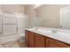 Bathroom featuring dual sinks, wooden cabinets, and a shower with sliding glass doors at 18060 W Rimrock St, Surprise, AZ 85388