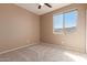 Neutral bedroom features carpet and ceiling fan plus a large window at 18060 W Rimrock St, Surprise, AZ 85388