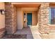 Inviting front porch with stone accents and a charming teal front door at 18060 W Rimrock St, Surprise, AZ 85388