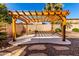 Backyard featuring a modern pergola, xeriscaping, and a privacy wall, offering a secluded outdoor space at 18060 W Rimrock St, Surprise, AZ 85388