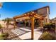 Backyard featuring a detached pergola, manicured landscape, decorative rock and an expansive two-story home at 18060 W Rimrock St, Surprise, AZ 85388