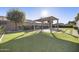 Manicured backyard featuring artificial turf, a covered patio, and desert landscaping at 19235 E Peartree Ln, Queen Creek, AZ 85142