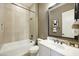 Modern bathroom featuring a tiled shower-tub, neutral-colored walls, a white vanity, and a decorative mirror at 19235 E Peartree Ln, Queen Creek, AZ 85142
