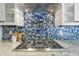Close-up view of a kitchen range with a pot filler and blue tile backsplash at 19235 E Peartree Ln, Queen Creek, AZ 85142