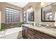 Bright bathroom featuring a soaking tub, tile accents, granite countertops, and dual sinks at 20529 N 94Th Ln, Peoria, AZ 85382