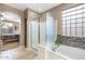Bright bathroom featuring a glass shower, soaking tub, and natural light from the glass block window at 20529 N 94Th Ln, Peoria, AZ 85382