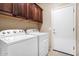 Functional laundry room with upper cabinets, washer, and dryer with a convenient exterior door at 20529 N 94Th Ln, Peoria, AZ 85382