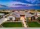 Stunning aerial view of a luxury home with beautiful landscaping, pool, and city views during twilight at 2656 E Oriole Dr, Gilbert, AZ 85297