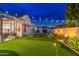 A well-manicured backyard with a putting green, fire pits, and stylish patio furniture under decorative string lights at 2656 E Oriole Dr, Gilbert, AZ 85297